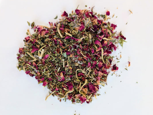 Heart-shaped arrangement of dried pink and green herbs on a white background