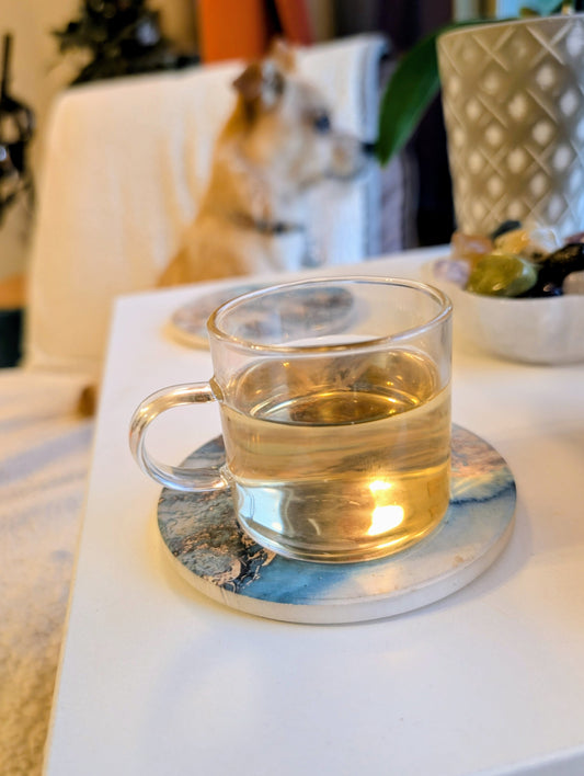 Clear glass mug with tea on a coaster on a table with a blurred background
