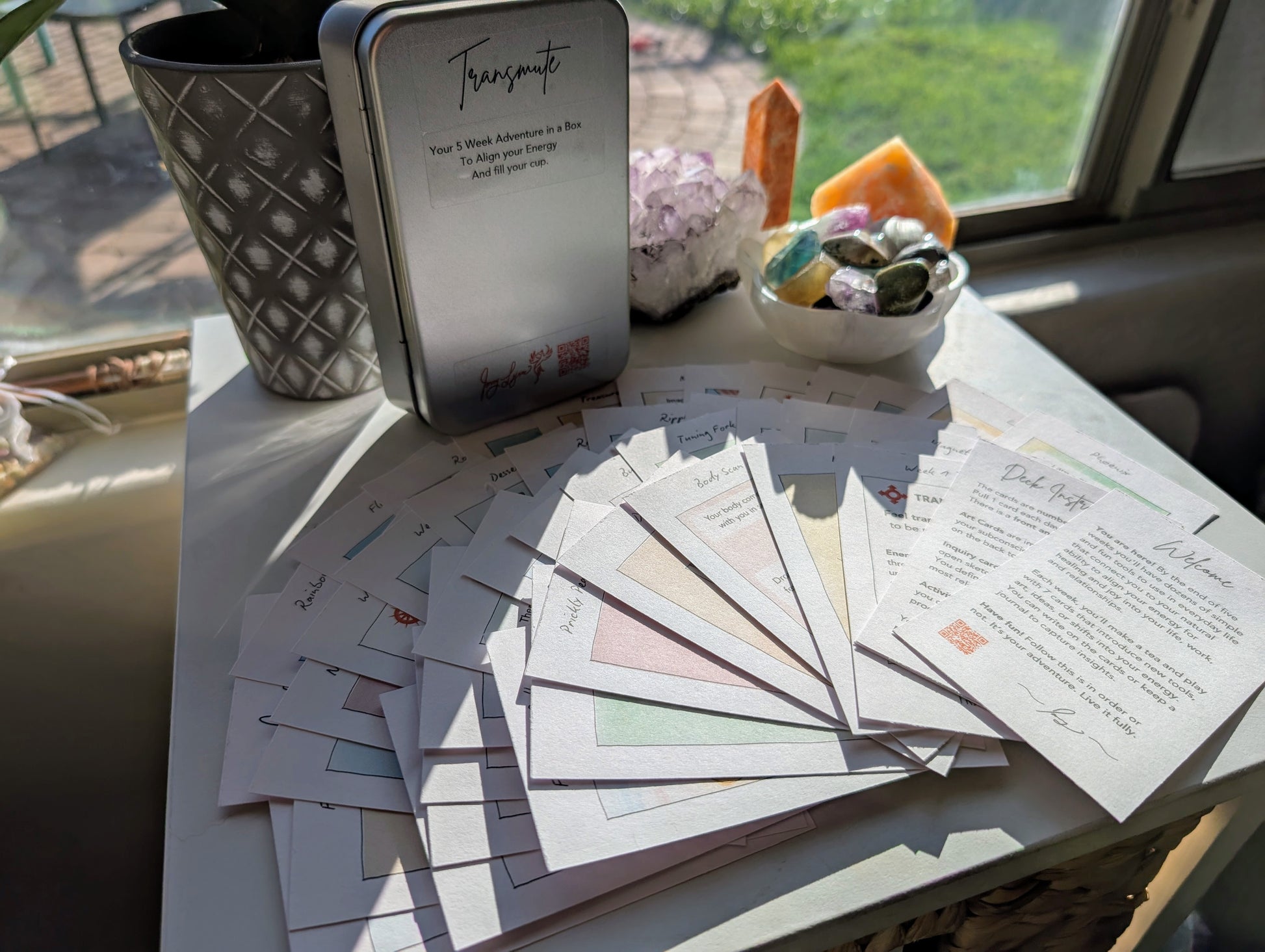 Table with 3x5 art and activity cards on index card stock, a metal tin labeled 'Transmute', and decorative items.