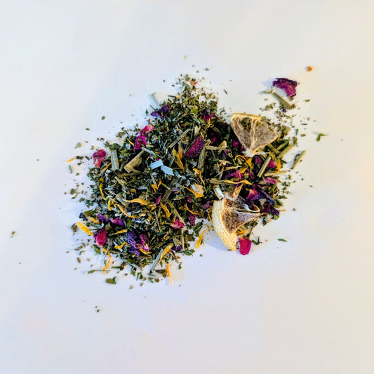 Assorted dried herbs and flowers, popping with rose petals, calendula, and lemon wedges on a white background